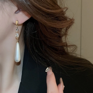 Eleganti orecchini a goccia dorati con cristalli e una grande perla bianca a goccia