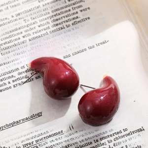 Macro shot of red teardrop enamel earrings on a vintage book page backdrop