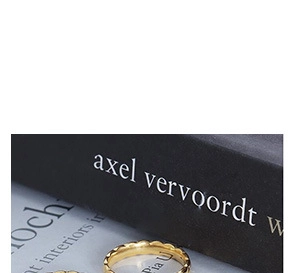 Macro shot of gold stainless steel ring with elegant wavy band design on dark book