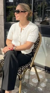 Close-up of white short-sleeved knit cardigan with round neck and buttons