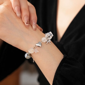 Close-up of beaded bracelet with silver bow pendants and transparent star beads on wrist