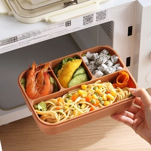Brown 4-compartment bento box being taken out of a white microwave oven by hand
