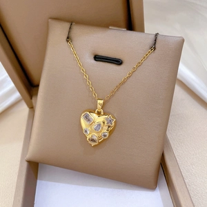 Detail of gold heart pendant necklace inlaid with multi-shaped sparkling crystals on beige pad