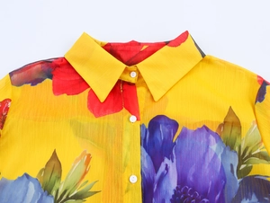 Detail of floral print chiffon shirt featuring lapel collar and white buttons on yellow fabric