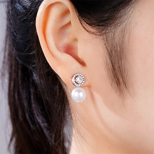 Elegant pearl stud earrings with zircon inlay worn by model to show product scale