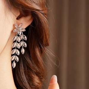 Close-up of model wearing silver flower leaf tassel earrings with clear crystal stones
