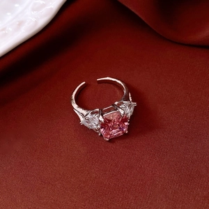 Detail of a square pink zircon ring on burgundy silk fabric with silver band