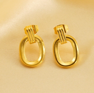 Detailed view of gold geometric hoop earrings on champagne satin fabric background