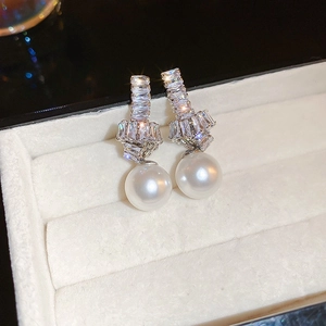 Detail of silver knot earrings with sparkling cubic zirconia and white faux pearls