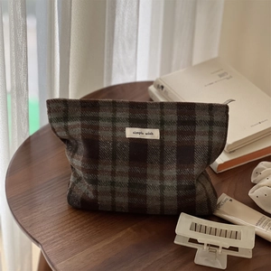 Retro plaid wool makeup bag with simple wish label on a vintage wooden table