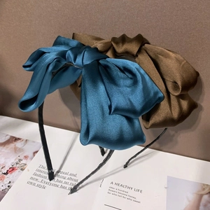 Détail de serre-têtes en satin bleu et marron avec grands nœuds sur un magazine