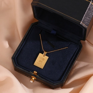 Detailed macro view of an 18K gold-plated square pendant with a hand and sun totem