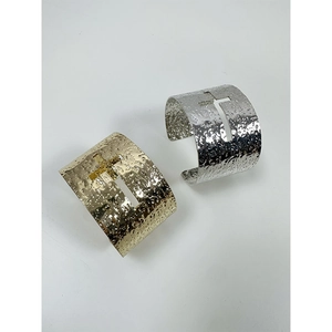 Detail of hammered texture and cutout cross on gold and silver wide open cuffs