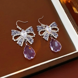 Detail of elegant bow earrings with purple teardrop crystals in a jewelry box