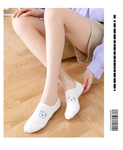Detail of white low cut socks featuring a small blue cartoon bear face on soft cotton fabric