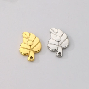 Detailed macro view of hollow leaf pendants in polished gold and silver stainless steel