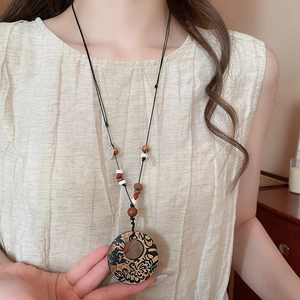 Detailansicht der Boho-Halskette mit rundem Blumenanhänger und Holzperlen auf Leinen