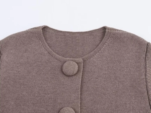 Macro detail of the round neckline and fabric-wrapped button on the taupe knitted cardigan
