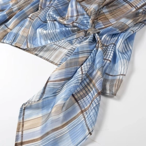 Detailed view of blue and brown plaid fabric with gold metallic thread and knot detail
