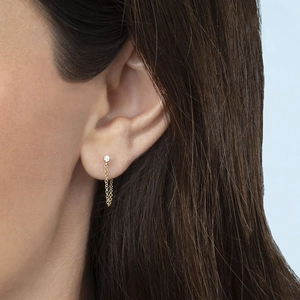 Close-up of gold tassel drop earring with sparkling zircon stud on model's ear