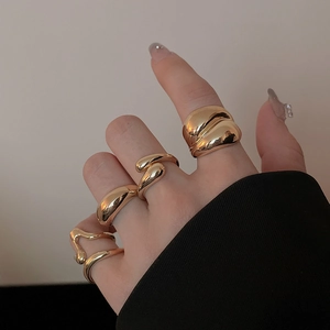 Close-up of four minimalist irregular gold-plated bean rings worn on a model hand