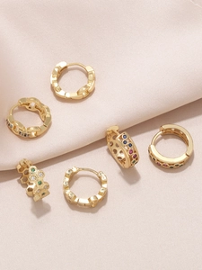 Gros plan de boucles d'oreilles créoles dorées avec zircons colorés sur tissu en soie rose