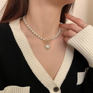 Detail of French vintage pearl necklace featuring a golden heart pendant and OT clasp buckle