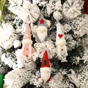 Set of 4 knitted Christmas gnome ornaments with stars and hearts hanging on a snowy tree