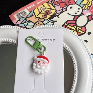 Detail of cute Santa Claus keychain with green metal clasp on festive gift packaging