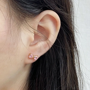 Close-up of bow earrings with pink heart gemstones on gold metal for women