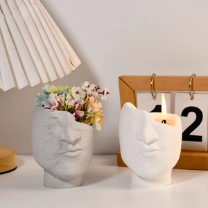 Detailed view of handmade face-shaped planters used as flower vases and candle holders