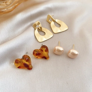 Three pairs of geometric leopard print and amber heart studs on elegant silk fabric