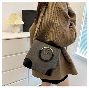 Close-up of stylish gray monogram bucket bag worn with a brown knit sweater