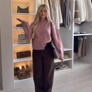 Chic pink knit cardigan with round buttons and pockets paired with brown wide-leg pants