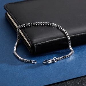 Detailed close-up of a silver stainless steel box chain bracelet with a lobster clasp