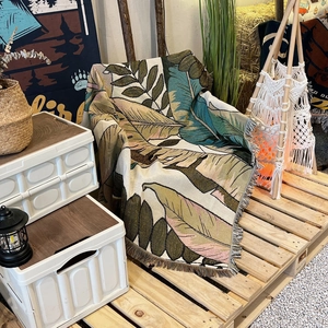 Detail of bohemian woven camping blanket with tropical palm leaf patterns and fringe edges