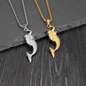 Detailed comparison of gold and silver mermaid pendants with box chains on stone surface