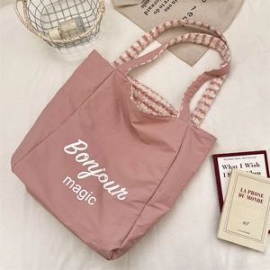 Detail view of pink canvas tote bag with Bonjour magic print and plush striped handles