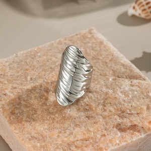Close-up of a silver textured ring with shell patterns on a natural stone background