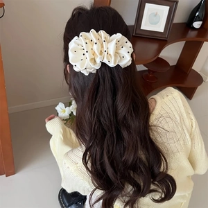 Satin polka dot oversized scrunchie for women shown in a cream white and black hair bun style