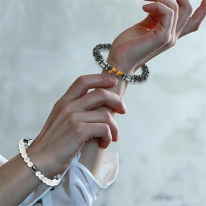 Detail of white turquoise and magnetic bead bracelets with tiger eye stones on model