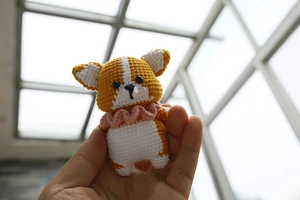 Close-up of handmade crochet Corgi dog plush with a pink collar for bag decoration