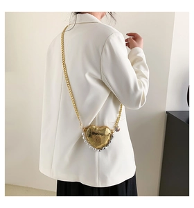 Détail du mini sac doré en forme de cœur avec texture serpent et bordure en perles