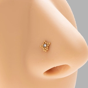 Close-up of golden geometric nose stud with round zircon on silicone nose model