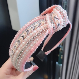 Macro detail of pink tweed headband with pearls, sequins, and braided texture