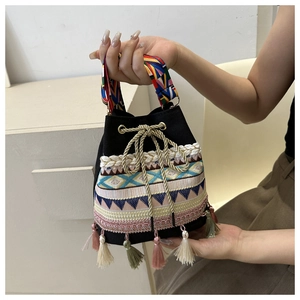 Detail of ethnic embroidered bucket bag with colorful tassels and woven straps