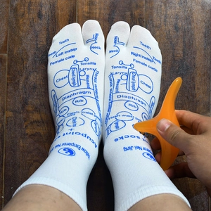 Acupoint massage socks with blue reflexology charts and orange massage tool on feet