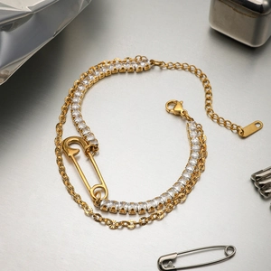 Vue détaillée de la gourmette dorée double couche et du bracelet tennis en zircon