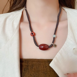 Detailed view of handmade rope necklace with red agate stone and vintage metal charm