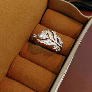 Gros plan d'une bague plume en argent sertie de zircon dans une boîte en daim marron